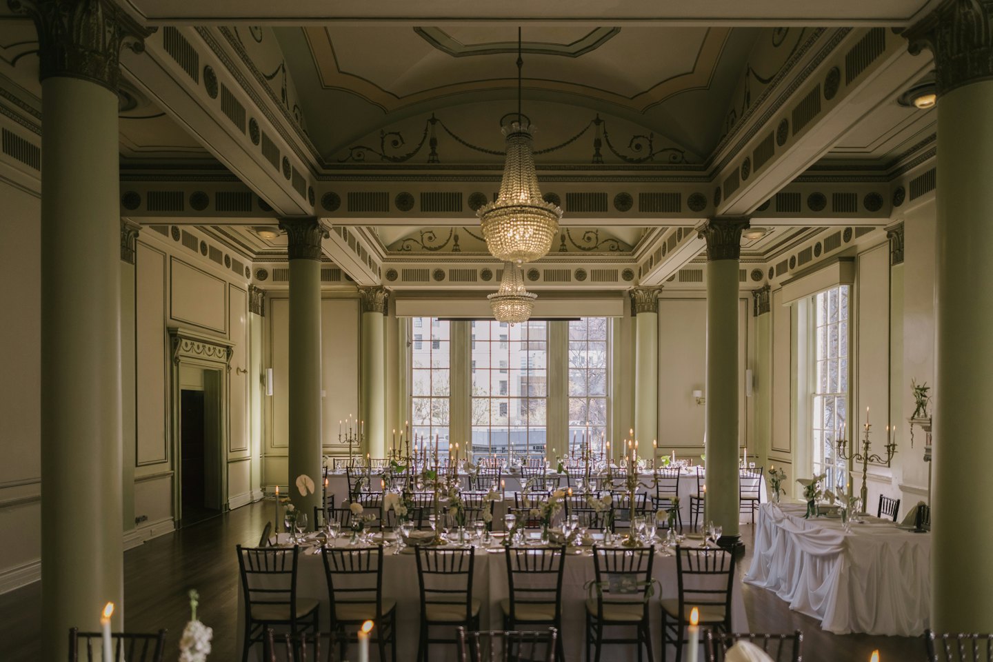 Eleganter Ballsaal mit kerzenbeleuchteten Tischen und Blumengestecken.